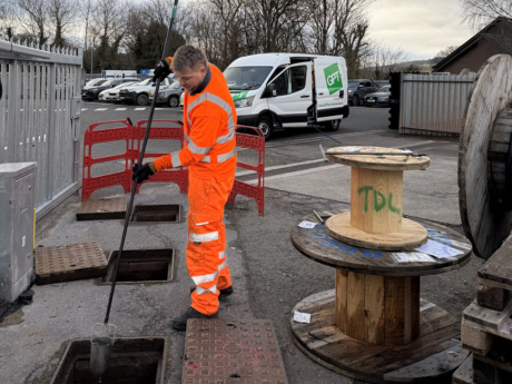 gpt field engineer inspecting an interceptor taking a water sample with gpt van in the background