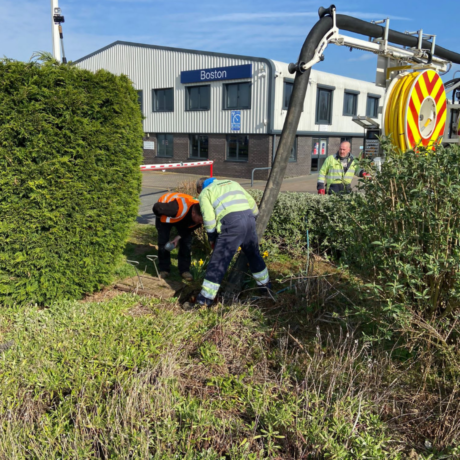 field engineers using vacuum excavation equipment to suck water and silt from interceptor near office building